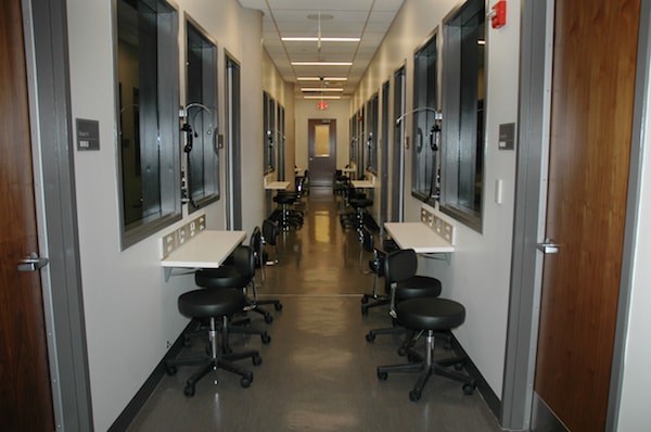 A narrow corridor where people can observe inside different rooms.