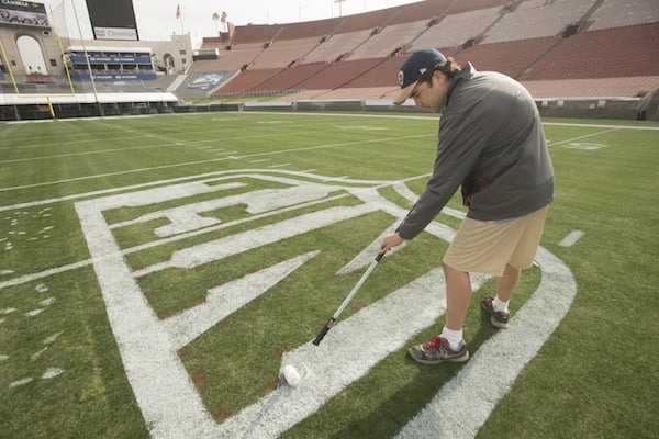 Sean McLaughlin paints the NFL logo on the grass in an empty stadium