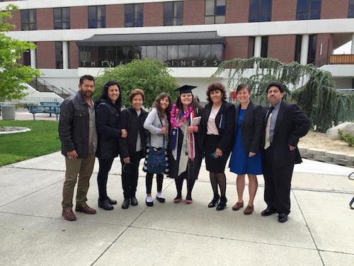 Padilla-Rodríguez in a cap, gown and graduation lei stands with family at her graduation.
