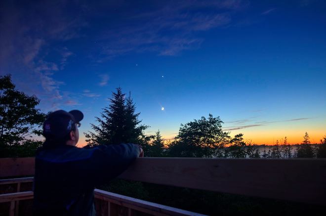 Tim faces away from the camera and faces a clear sky with a setting sun.