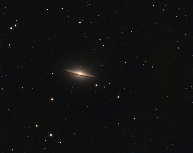 Among tiny stars, there's a glowing cloud with a ring around a bright sun.