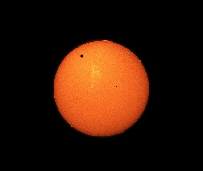 A small dot (Venus) crosses the top half of our glowing molting sun.