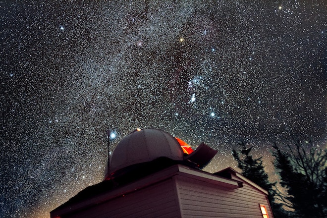 An observatory is in the foreground and millions of stars are visible in the background.