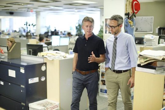 Two reporters in a busy and messy newsroom.