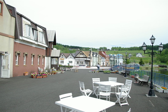 A row of provincial buildings with empty white picnic tables.